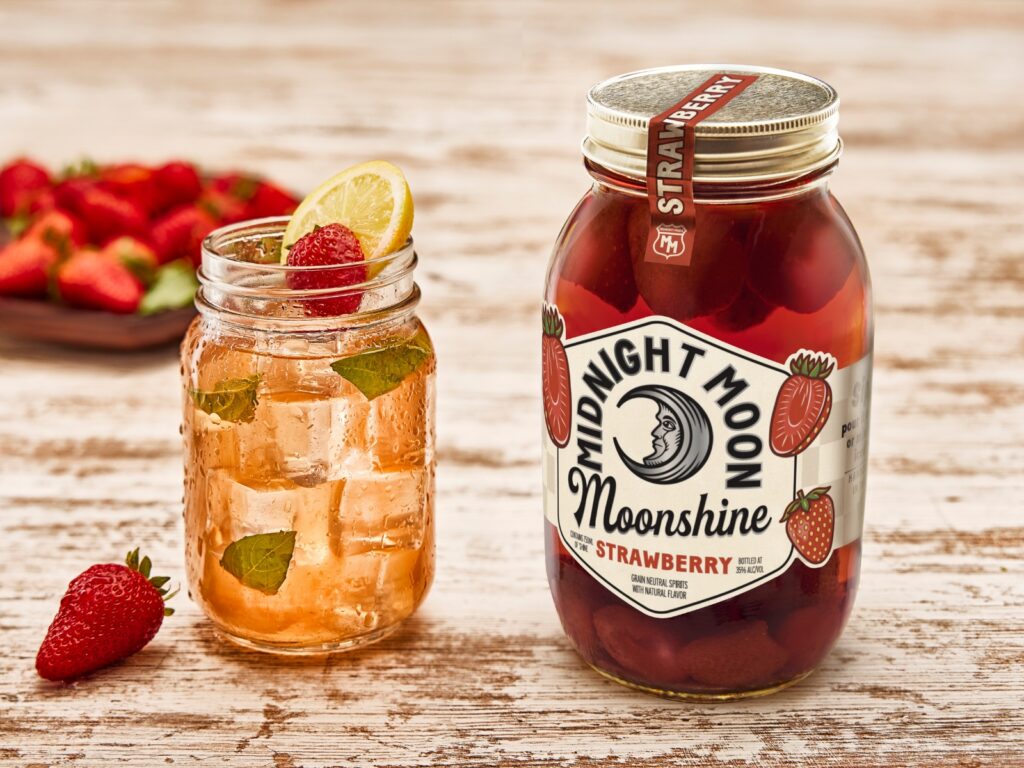 Strawberry moonshine basil lemonade next to Midnight Moon Strawberry Moonshine jar