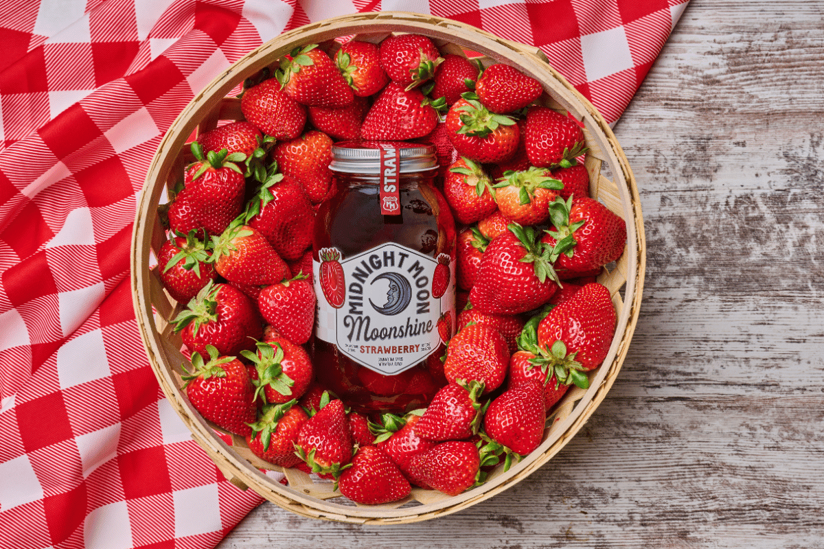 Midnight Moon Strawberry Moonshine in a basket of fresh strawberries