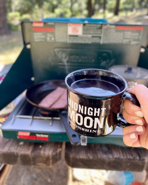 Hand holding campfire mug while cooking