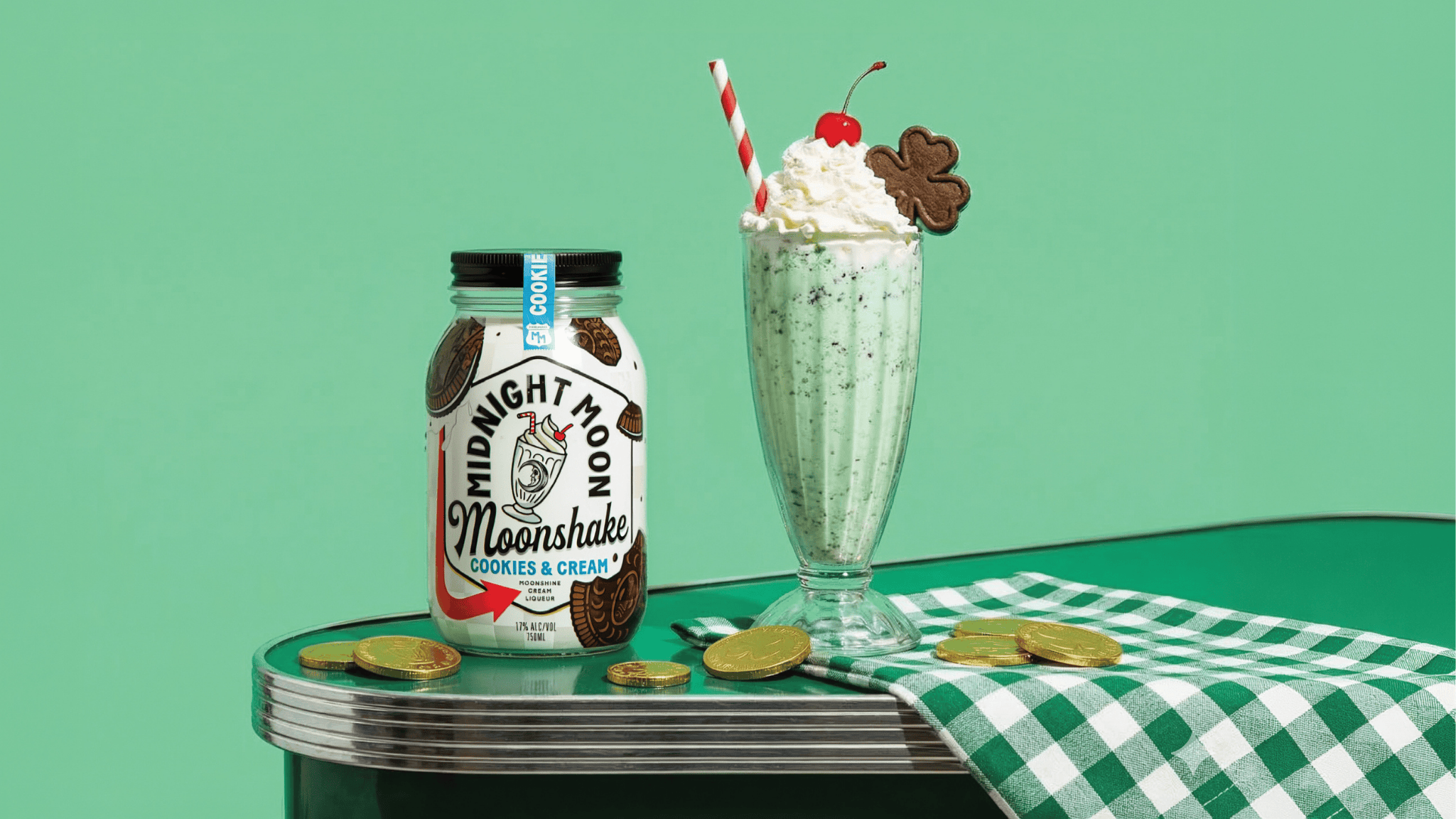 A jar of Midnight Moon Cookies & Cream Moonshake on a diner counter next to a mint chocolate chip milkshake
